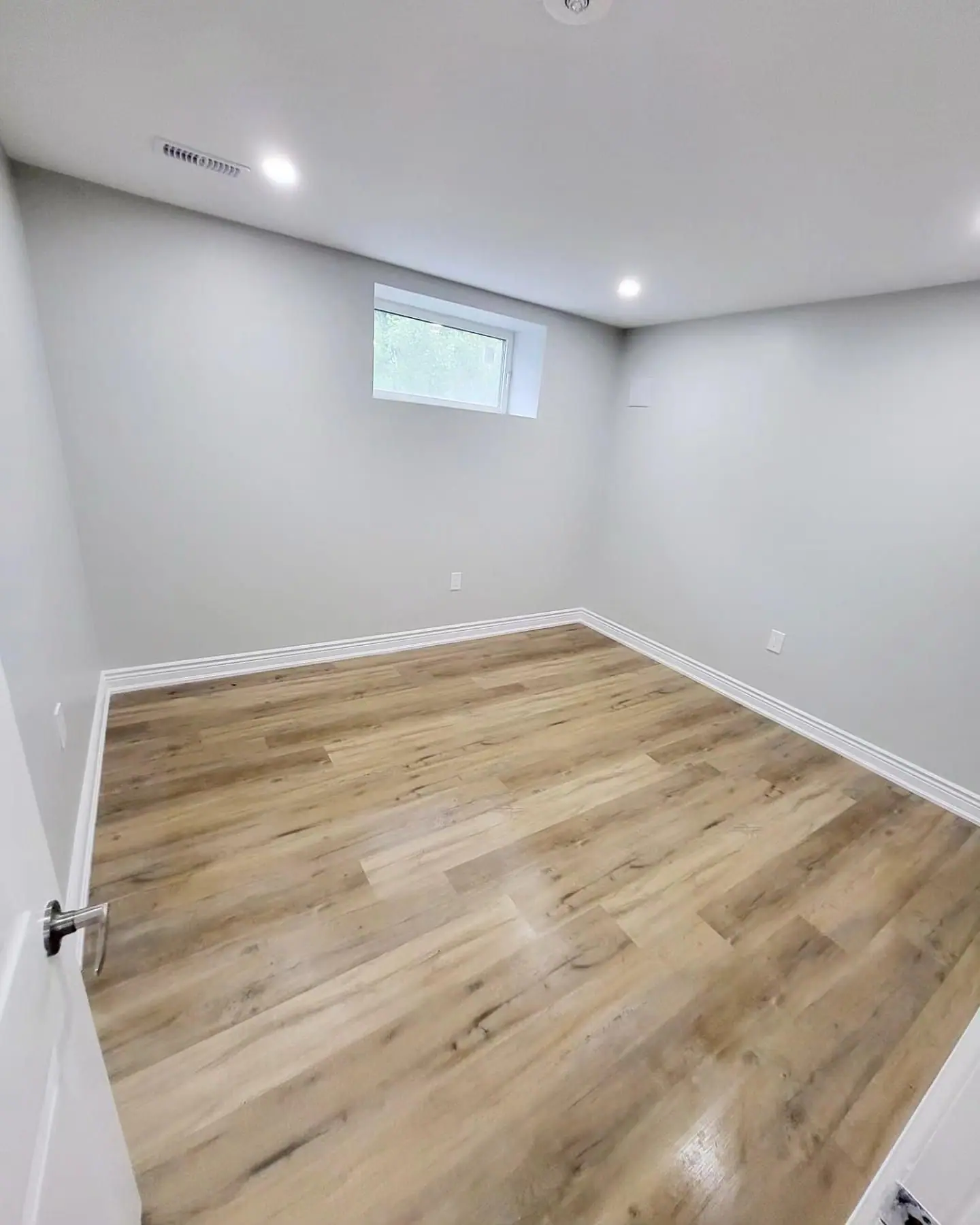 Basement bedroom with window and light vinyl plank floor