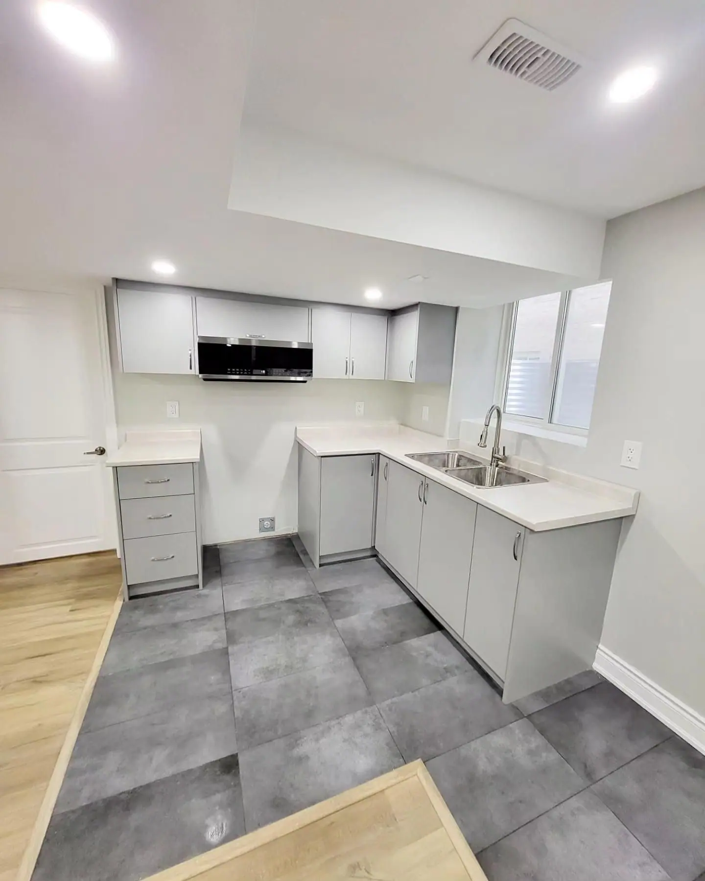 Basement suite kitchen with grey shaker cabinets and porcelain tile floor