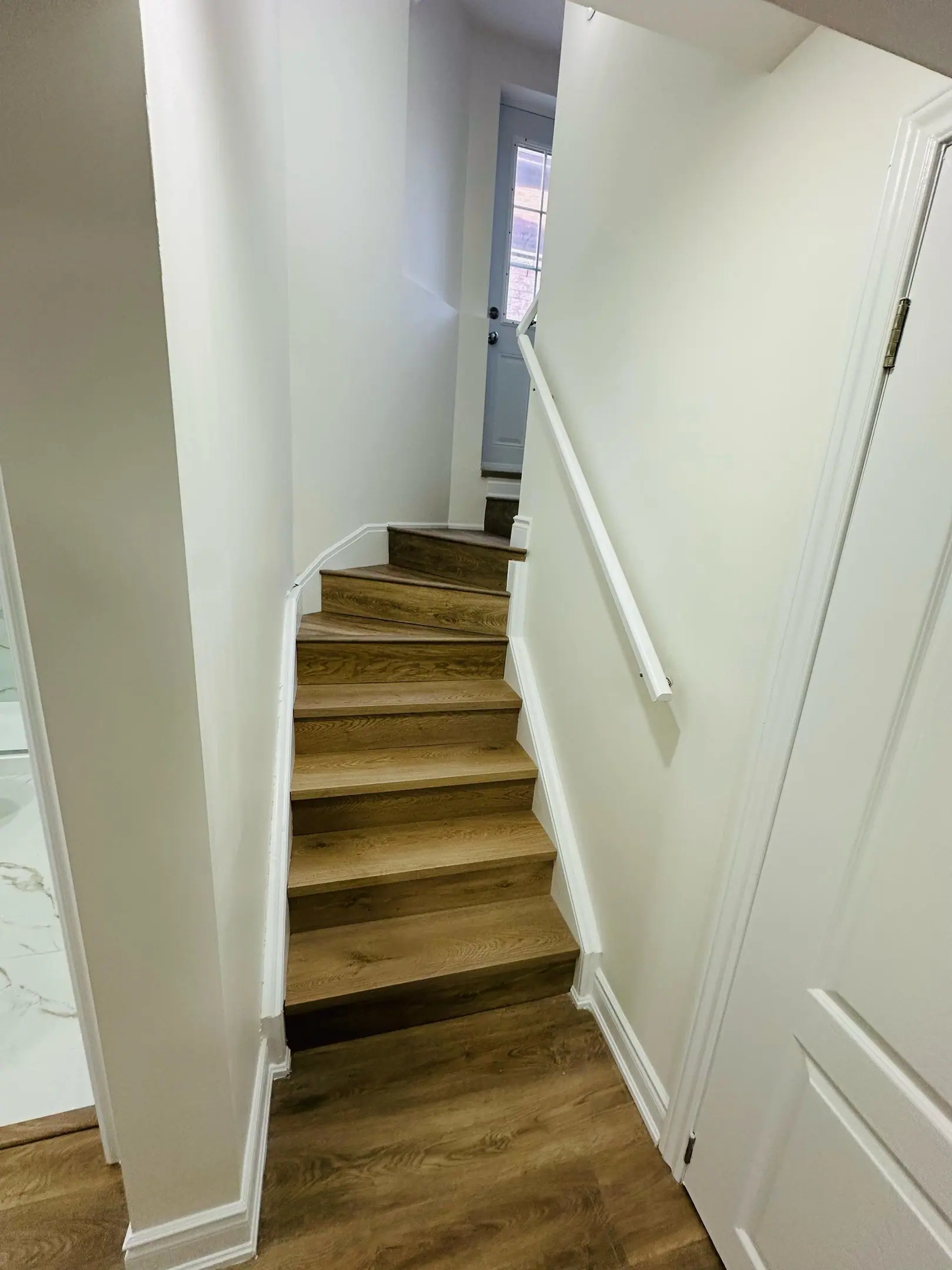 Narrow stairway into a finished basement with wood treads