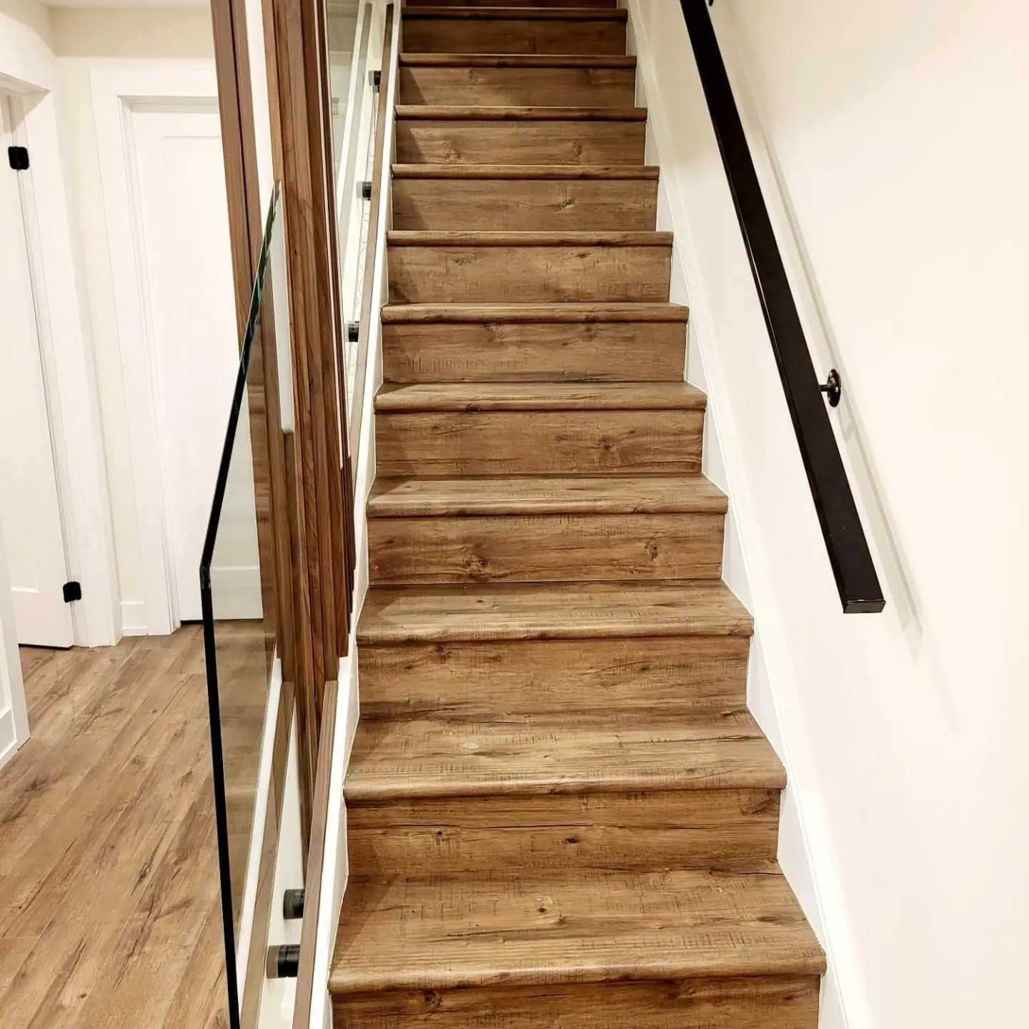 Oak stair treads with black handrail leading down to a finished basement