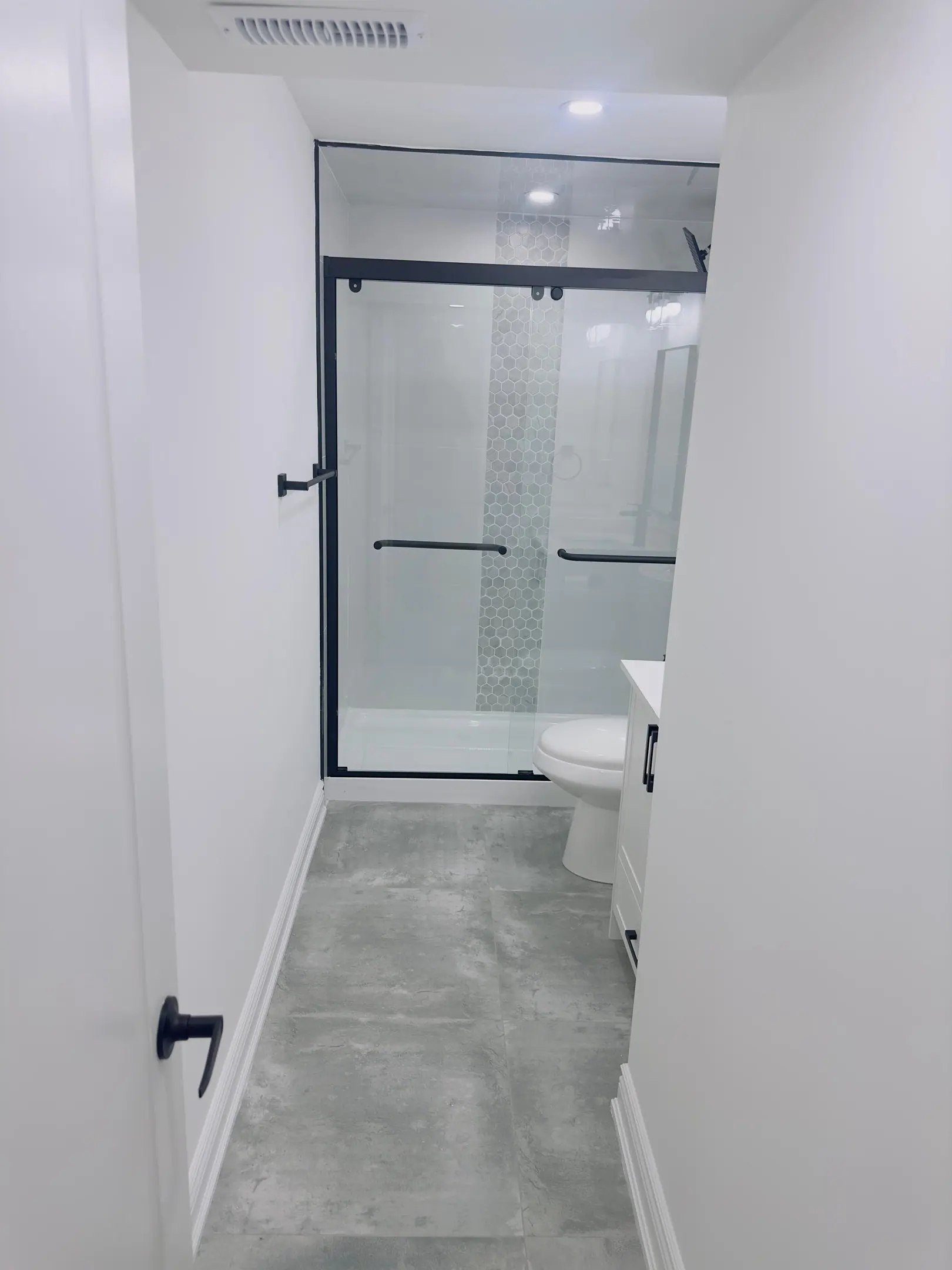 Basement bathroom with glass shower and grey tile