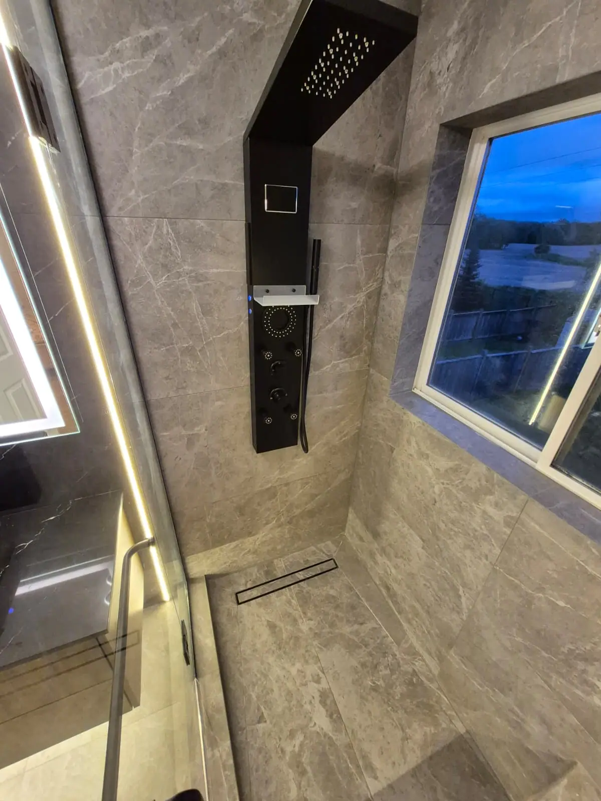Shower with rainfall shower panel and linear drain