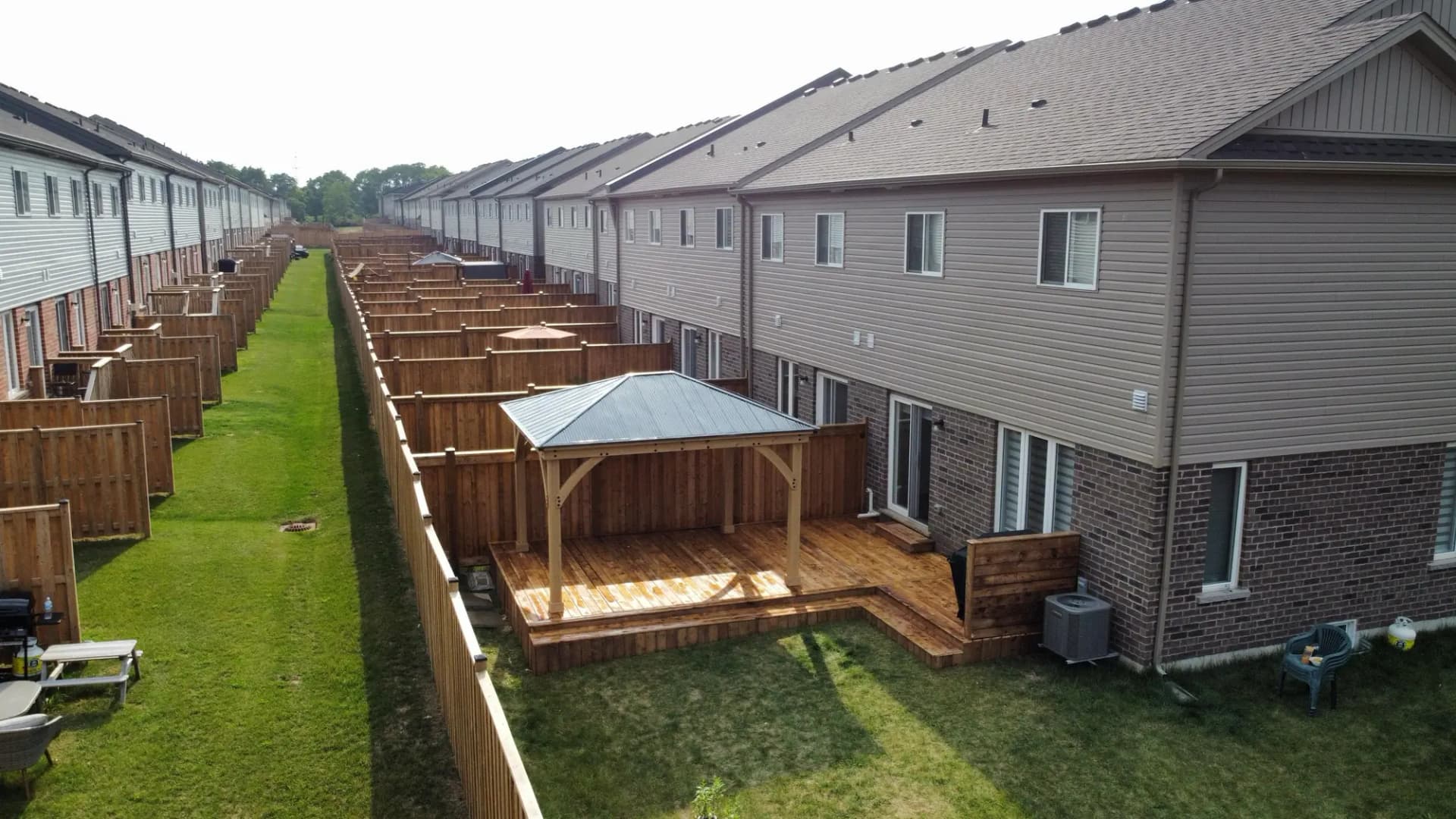 Aerial view of backyard decks and a gazebo behind townhouses