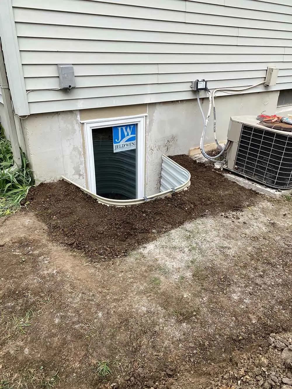 Egress window well excavated beside a house foundation