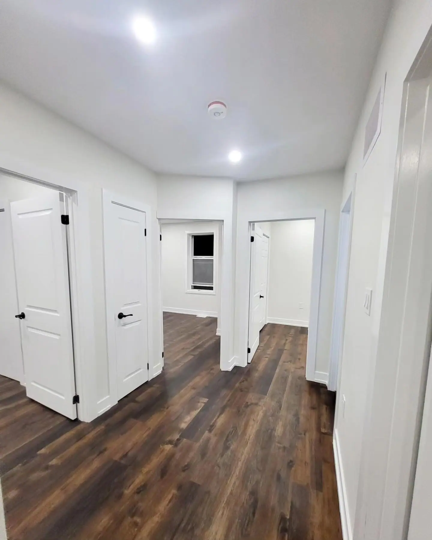 Hallway with wide-plank vinyl flooring and white trim