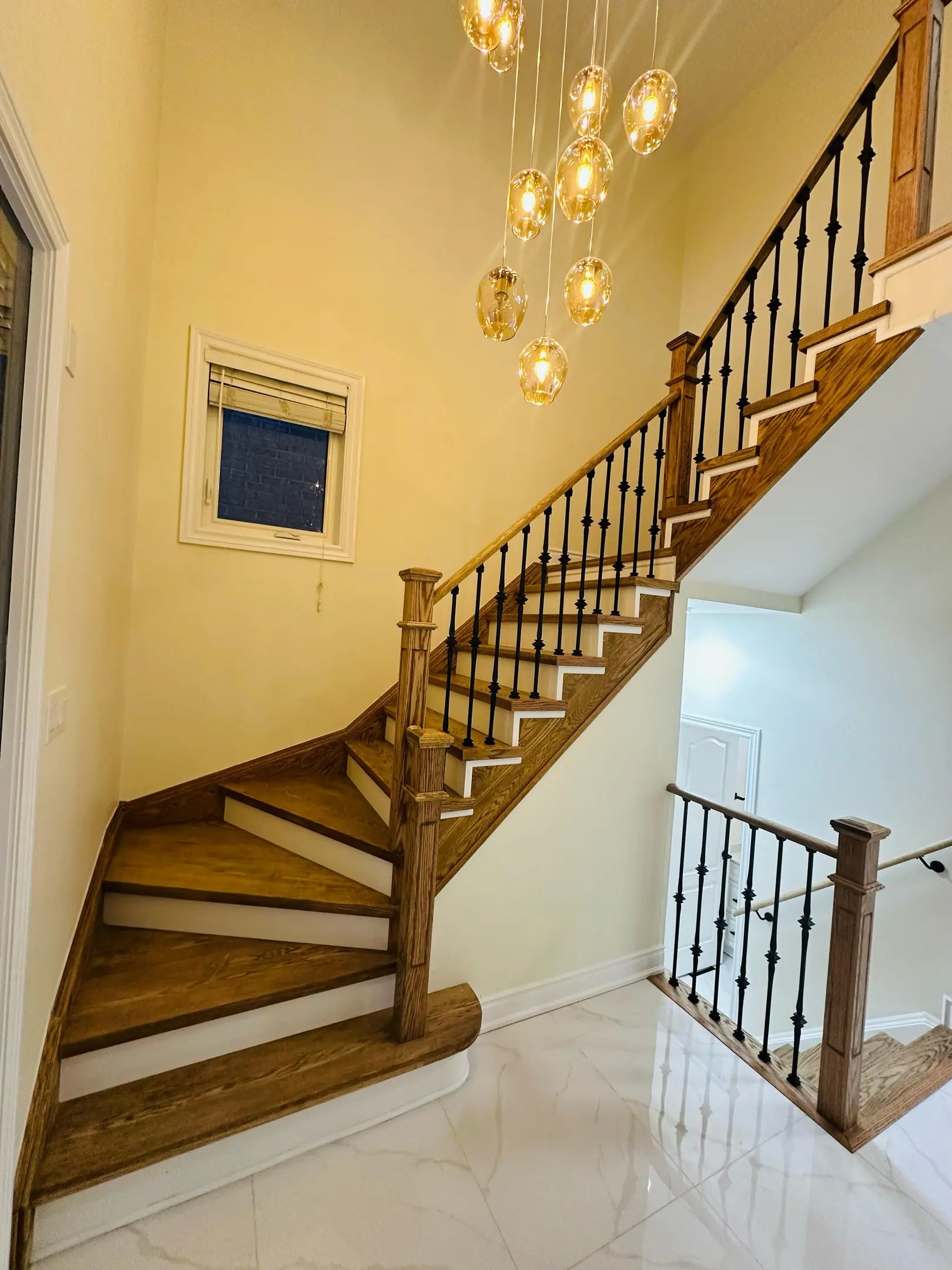 Curved oak staircase with wrought-iron pickets and porcelain foyer
