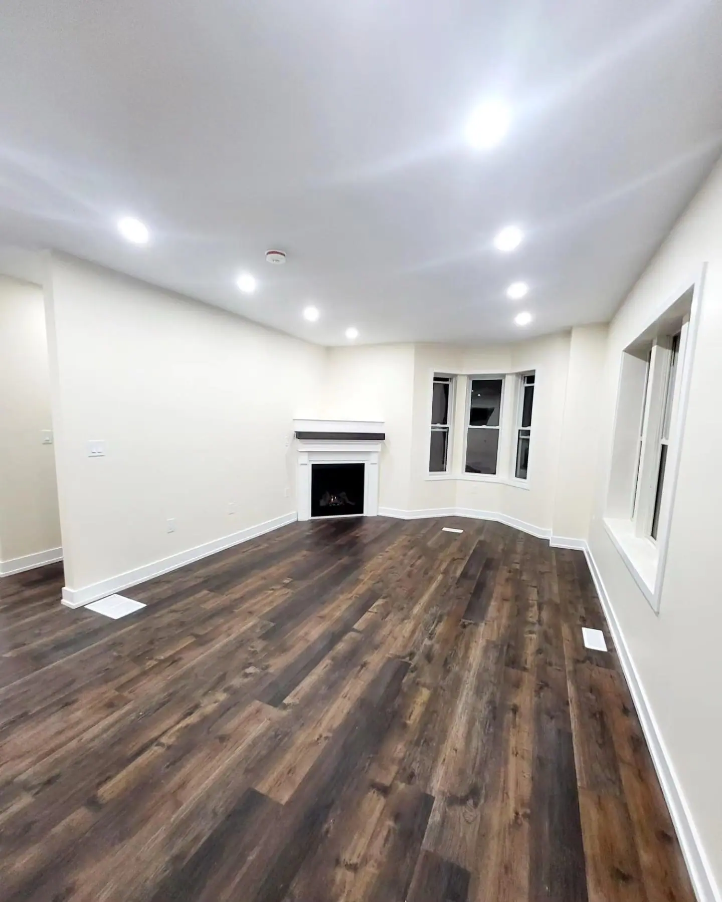 Living room with corner gas fireplace and dark plank floor