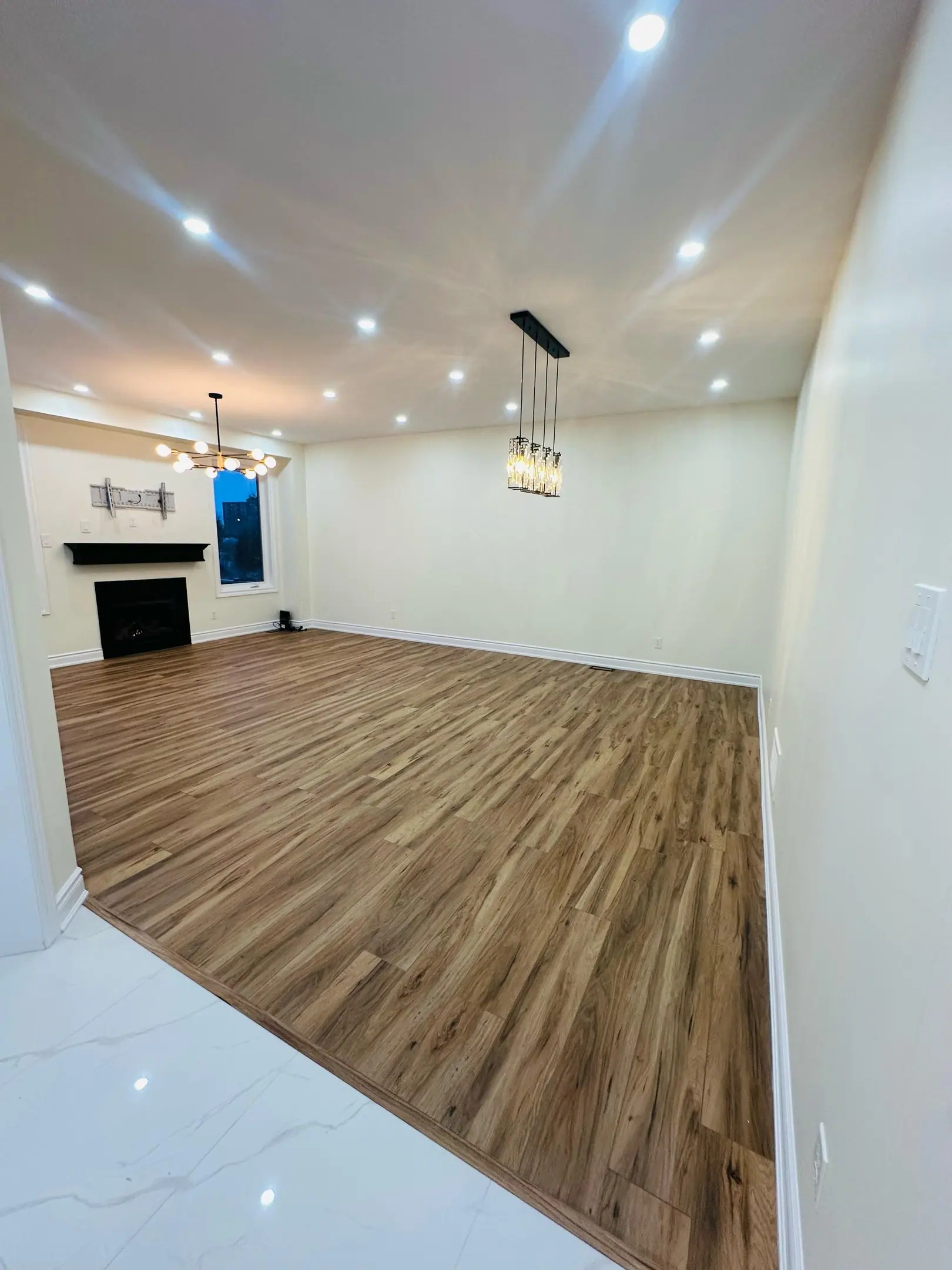 Open living and dining area with chandeliers and new flooring