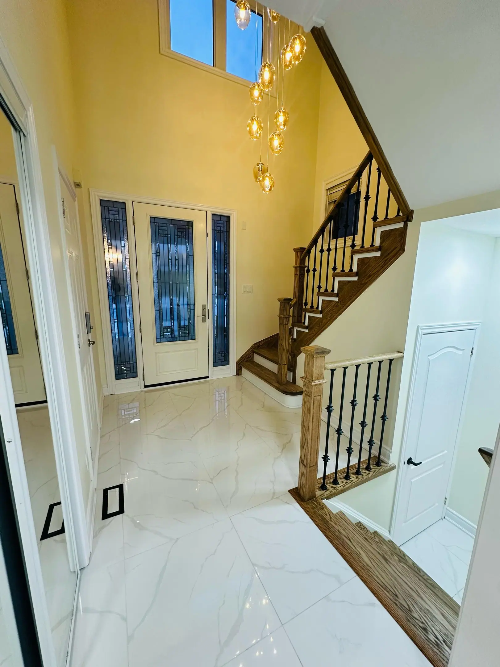 Two-storey foyer with oak stairs, iron pickets and porcelain tile