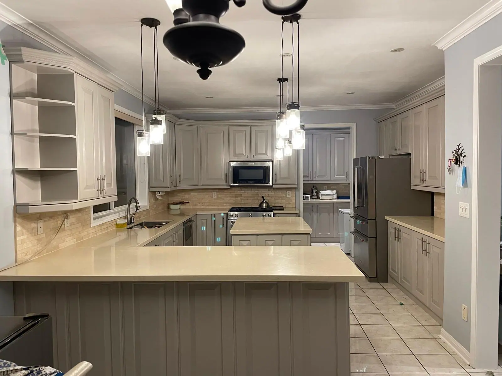 Kitchen with grey cabinets, peninsula and pendant lights